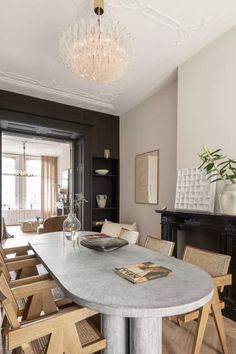 a dining room table with chairs and a chandelier hanging from the ceiling above it