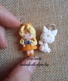 a person holding two small key chains in their left hand and a cat on the other