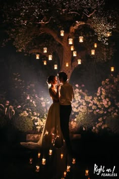 a man and woman standing in front of a tree with lanterns hanging from it's branches