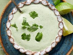 a blue plate topped with a small bowl filled with guacamole and garnished with cilantro