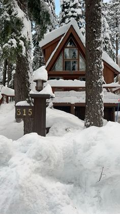 a cabin in the woods with snow on the ground and trees covered in snow around it