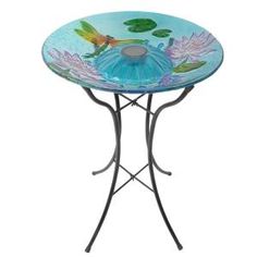 a glass table with flowers and dragonflies on it