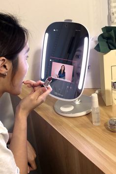 a woman is looking at her reflection in the mirror while she brushes her teeth with an electric toothbrush