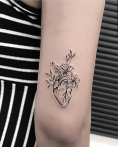 a heart tattoo with flowers on the arm