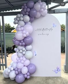 the balloon arch is decorated with purple and white balloons