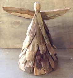 an angel made out of driftwood sitting on top of a wooden table next to a wall