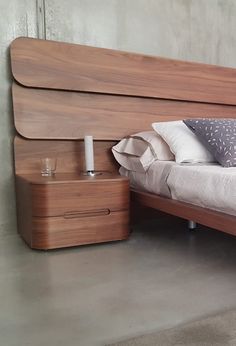 a bed with wooden headboard and foot board next to a night stand on concrete floor