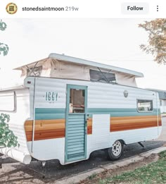 an old trailer is parked on the side of the road in front of a tree