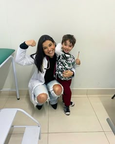 a woman sitting next to a little boy on the floor in front of a chair