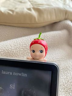 a small doll sitting on top of a tablet computer next to a stuffed animal toy