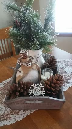 a wooden tray filled with pine cones and other decorations