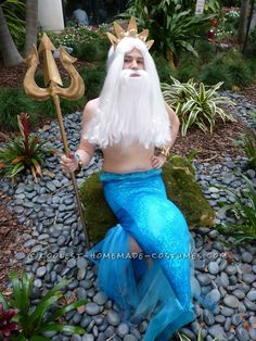 a man dressed as a mermaid sitting on rocks