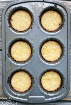 a muffin tin filled with yellow cupcakes on top of a wooden table