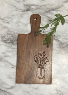 a cutting board with flowers on it sitting on a marble counter next to a plant