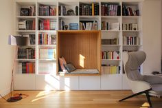 a living room filled with furniture and bookshelves next to a chair in front of a window