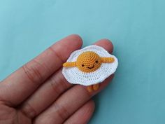 a small crocheted sheep is in the palm of someone's left hand