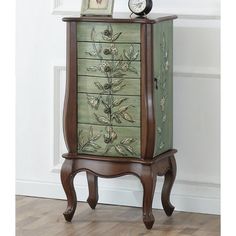 a green cabinet with flowers painted on the front and drawers, sitting against a white wall