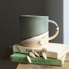 two books stacked on top of each other with a coffee mug sitting on top of them