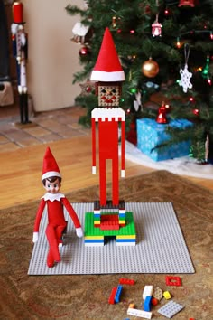 an elf is standing next to a lego christmas tree