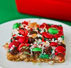 a white plate topped with a piece of cake covered in candy and m & m