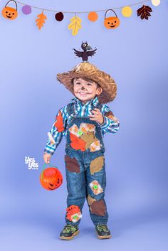 a little boy dressed up as a scarecrow holding a jack - o'- lantern