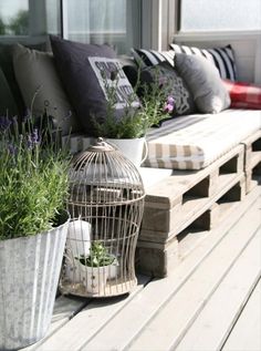 a birdcage sitting on top of a wooden bench next to two planters