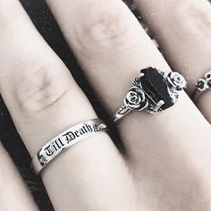 three different rings on someone's hand with their names engraved on the ring finger