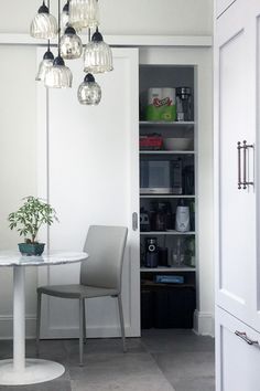 a white table and chairs in a room with a light fixture hanging from the ceiling