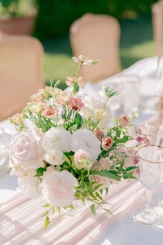 a bouquet of flowers is sitting on a table with wine glasses and napkins in front of it