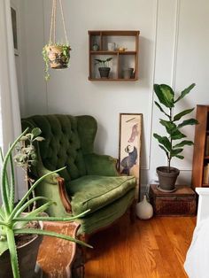 a living room with a green couch and potted plants on the wall next to it