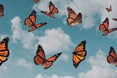 a group of orange butterflies flying through the air on a sunny day with clouds in the background