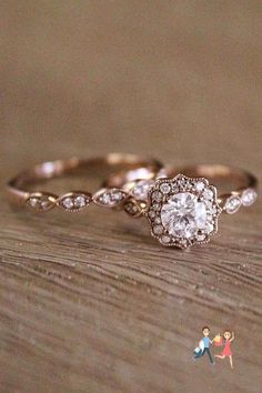 two wedding rings with one diamond on top and the other in gold, sitting on a wooden table