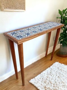 a wooden table sitting on top of a hard wood floor next to a potted plant