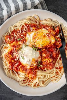 a white plate topped with pasta covered in sauce and an egg on top of it