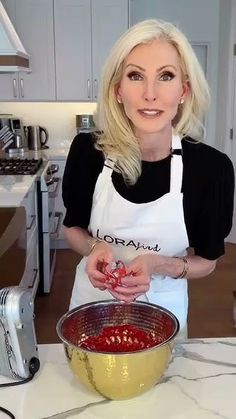 a woman in an apron is mixing food into a bowl on the kitchen counter top