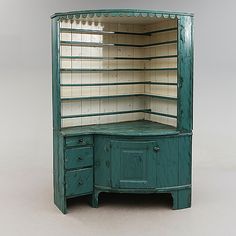 an old green cabinet with drawers and shelves