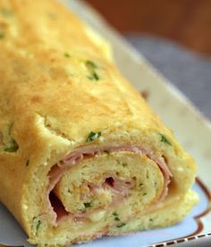 a ham and cheese roll on a plate with a napkin underneath it, ready to be eaten