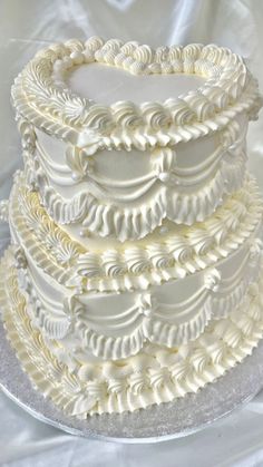 a three tiered cake with white frosting on a silver platter, ready to be cut