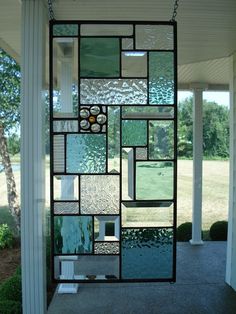 a stained glass window on the side of a house with grass and trees in the background