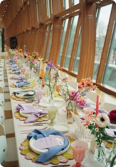 a long table is set with place settings and flowers