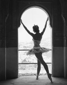 a ballerina is standing in front of an arch and holding her arms out to the side