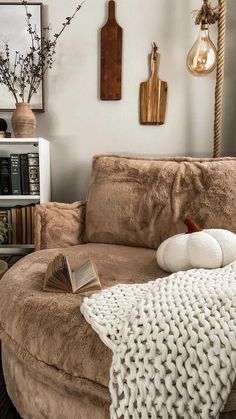 a living room filled with furniture and books on top of a brown ottoman covered in blankets