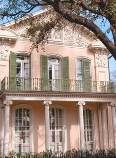 an old pink house with green shutters and balconies on the second story