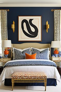 a bedroom with blue walls, white bedding and gold accents on the headboard