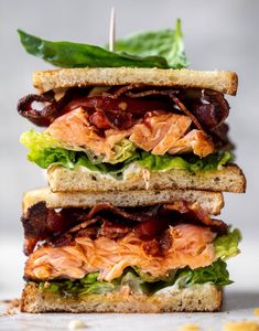 a sandwich with meat, lettuce and tomato on it is stacked high in the air