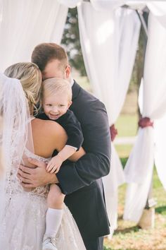 a man and woman hugging each other in front of a white tent