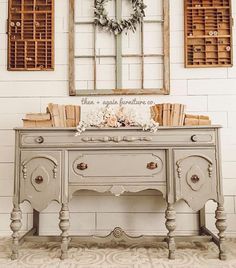 an old desk with wreaths on the top and two windows above it that have shutters in them