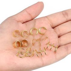 a person's hand holding several pairs of gold earring sets in their palm