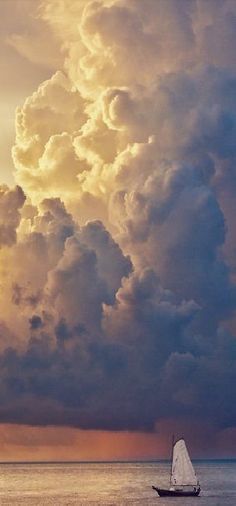 a sailboat in the ocean under a cloudy sky with sunbeams and clouds