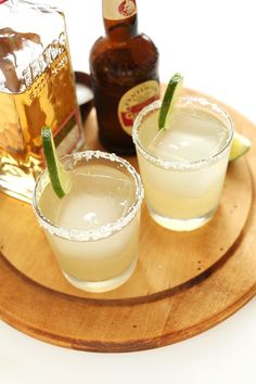 two glasses filled with drinks sitting on top of a wooden tray